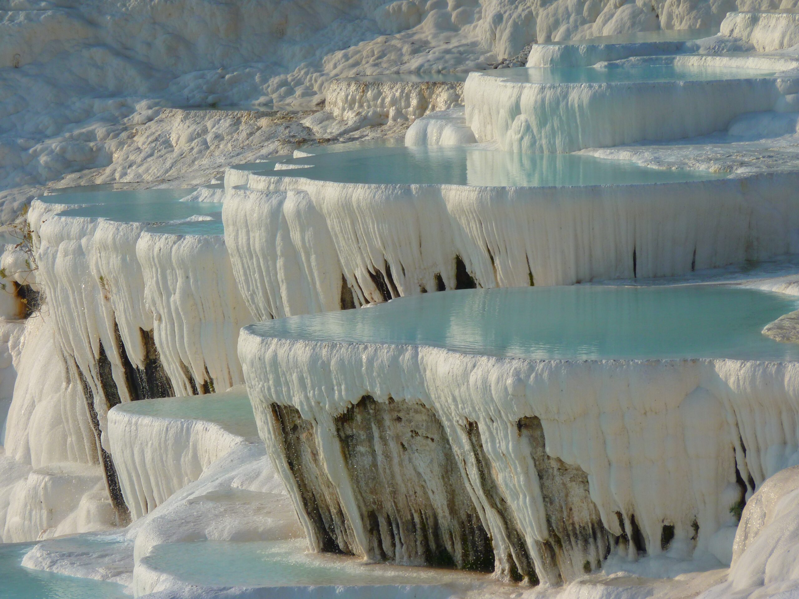 Pamukkale’deki kademeli beyaz traverten teraslarında biriken turkuaz renkli termal suların yakın çekim görüntüsü.